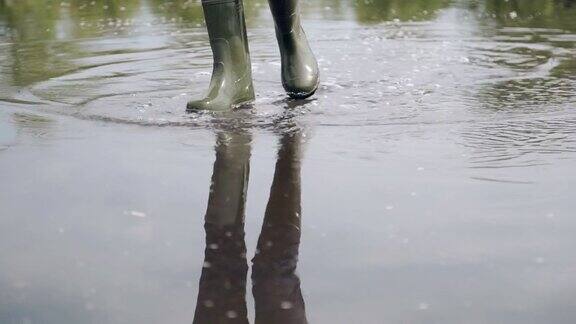 一个女孩在雨中的水坑里拿着伞的倒影