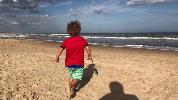 蹒跚学步的孩子在海滩上跑步