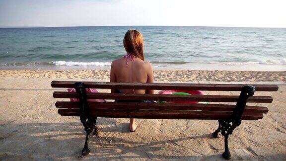 一个女人坐在长椅上看着大海