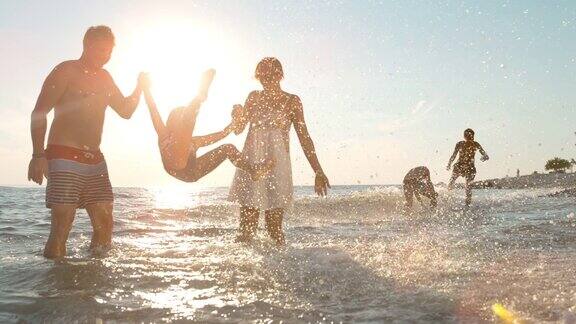 日落时分一家人和三个孩子在海滩上玩耍