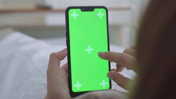 过肩拍摄的女性患者使用智能手机绿色屏幕