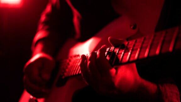手男人独奏吉他年轻音乐家在舞台上练习电吉他音乐会前检查声音在黑暗的房间里重金属音乐伴着五颜六色的霓虹灯