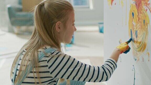 快乐的小女孩用手蘸黄蓝颜料在墙上画了一颗彩色的微笑的心她开心地笑着房屋正在装修