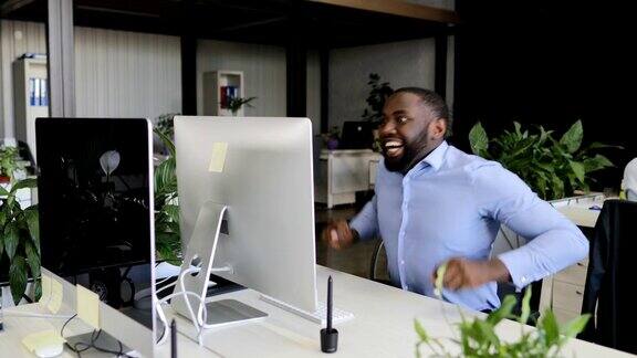 沉思的商人使用电脑获得成功兴奋的胜利快乐的非洲裔美国商人与商务人士团队在现代办公室欢呼