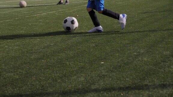 一个小男孩在足球场上训练他练习带球和射门