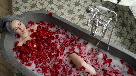 性感的女孩躺在一个大的石头浴盆里手里拿着一朵玫瑰
