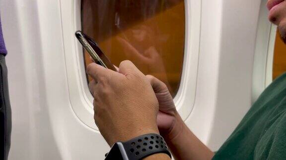 一名亚洲男子在飞机上使用智能手机