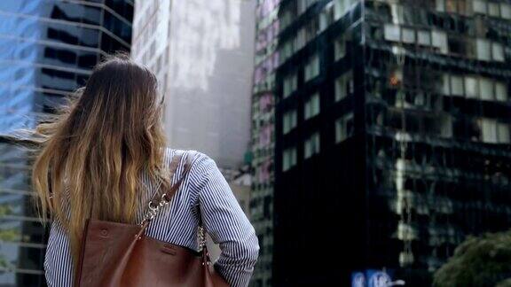 年轻的女商人拿着文件去美国纽约的办公楼的背影慢动作