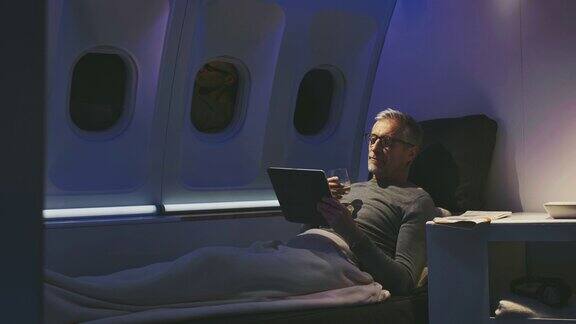 男性在飞机上使用平板电脑