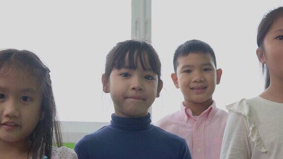 一群亚洲幼儿园的孩子正站在教室里他们很高兴对着镜头微笑