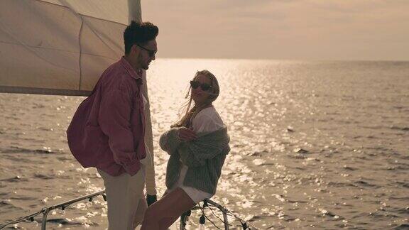 日落时分一对年轻的夫妇在一艘帆船的甲板上畅谈