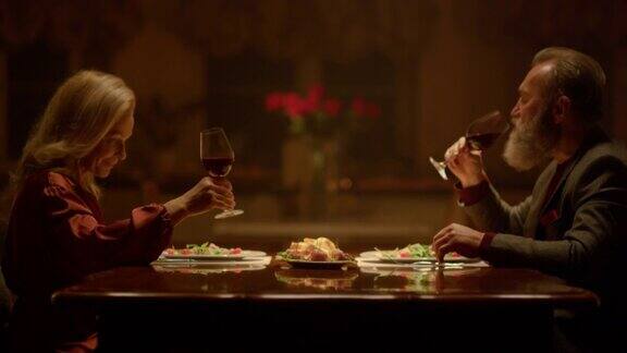老夫妇手握酒杯在餐厅里浪漫晚餐