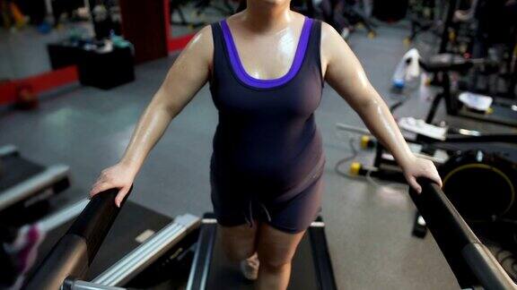 年轻女性用大肚子在跑步机上锻炼努力减肥