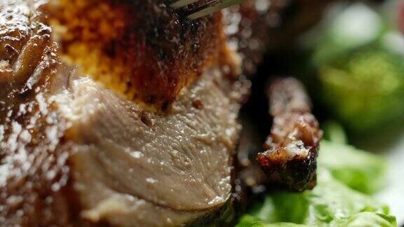 一把刀从烤鸭肉上切下一块多汁可口的鸭肉