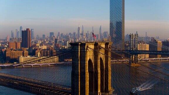 水上渡船正从布鲁克林大桥塔下经过顶上飘扬着美国国旗背景是远处的曼哈顿无人机视频与宽平移轨道电影摄像机运动