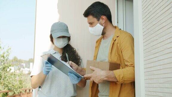 送货妇女和客户在医用口罩和手套交谈拿着包裹签名纸在户外