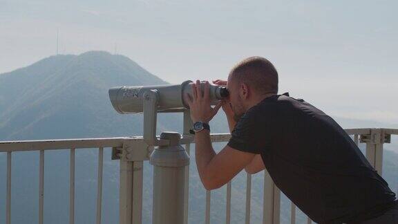 年轻游客用投币双筒望远镜观赏大自然
