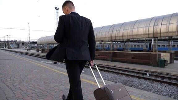 成功商人走过火车站拉着带轮子的行李箱