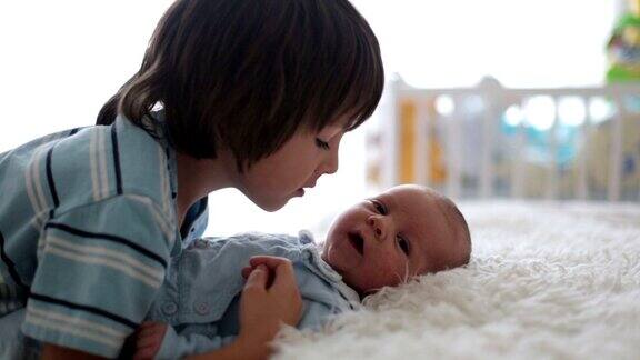 漂亮的男孩在家里温柔地拥抱和照顾他刚出生的弟弟亲情幸福观