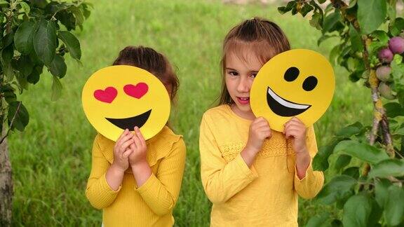 孩子们躲在写着快乐表情符号的纸板后面世界微笑表情符号日