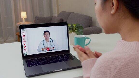 亚洲妇女与亚洲医生在家视频通话的后视图病人女孩在电脑上咨询全科医生的应用医生和顾问在线技术概念