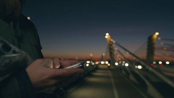 一名男子用智能手机捧着玫瑰花束黄昏时分在桥上发短信