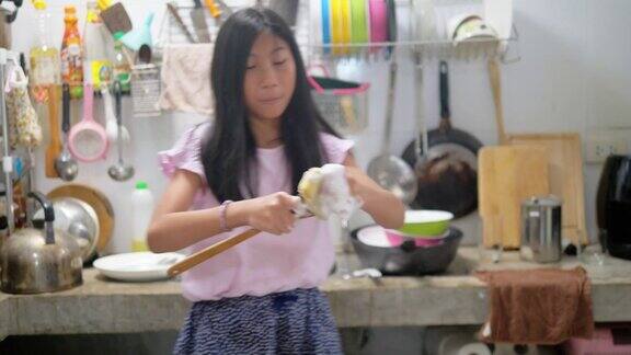 快乐的亚洲女孩在家里的厨房里洗碗跳舞生活方式