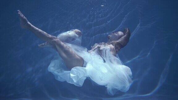 穿着白色裙子的长发女孩漂浮在水下