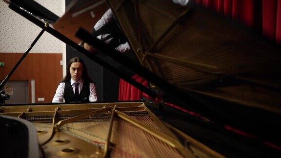一位才华横溢的年轻钢琴家在剧场里练习他的三角钢琴演奏技巧