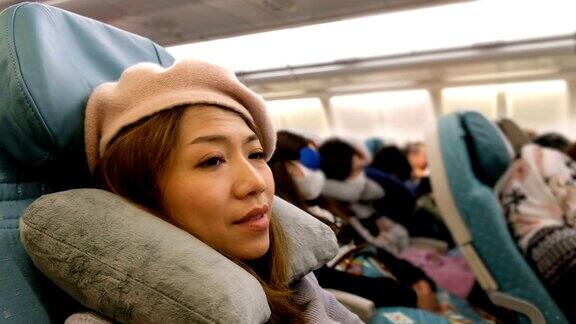 4K镜头:一名亚洲女子在飞机上从睡梦中醒来对长途战斗感到厌倦