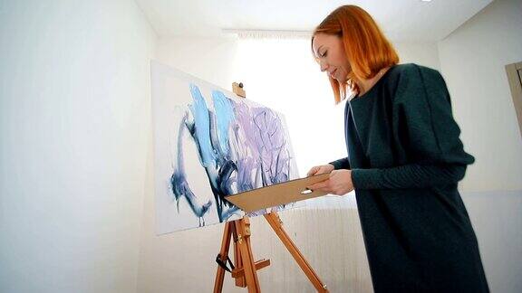 一位女艺术家开始用抹刀和丙烯颜料画一幅画在画布上绘制