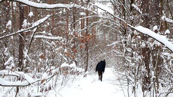 年轻人走在森林里一条被雪封住的小道上