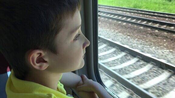 一个十几岁的男孩在行驶的火车上看窗外的风景