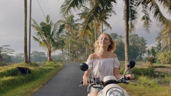 年轻女子骑摩托车在热带岛屿公路旅行享受摩托车旅行度假4k