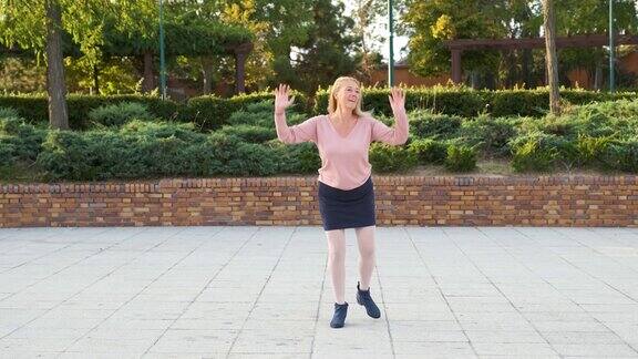 成熟的女子跳舞查尔斯顿在公园在街道