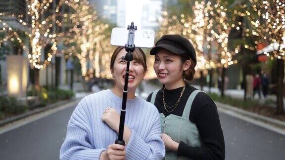 年轻的女性朋友在城市里用圣诞彩灯拍视频