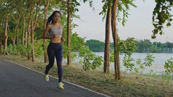 亚洲年轻美丽的女人为健康在傍晚日落在街道上的公园运动员健康和坚定的女孩锻炼通过慢跑锻炼户外运动为她的健康