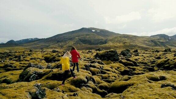 鸟瞰图两名妇女行走在冰岛的熔岩上探索这一领土欣赏风景的游客