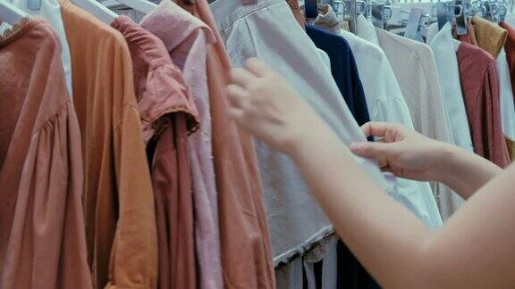 年轻的亚洲女人在商店购物中心选择衣服