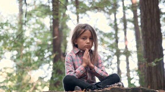 严肃的思考小女孩坐在树林里