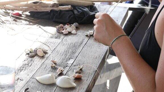 年轻女子用沙滩贝壳制作风铃
