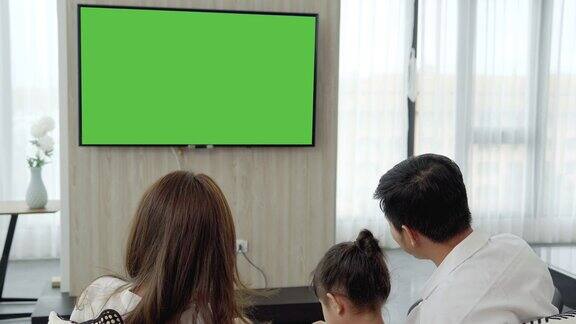 亚洲幸福家庭坐在家里的客厅看电视一起度过宝贵的时间频道到绿色屏幕显示器为您的信息