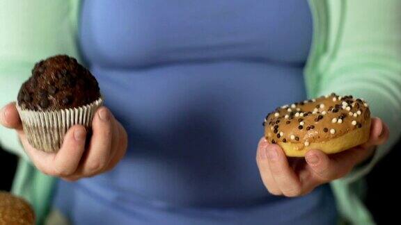 胖乎乎的女性手里拿着松饼和甜甜圈对甜食上瘾问题