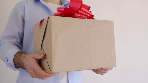 男人的手拿着一个带有红色蝴蝶结的礼品盒快递圣诞特卖在线购物情人节