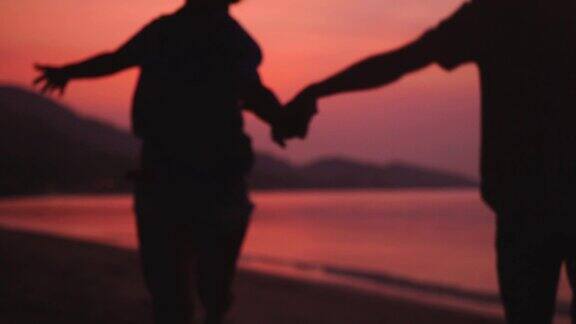 浪漫的情侣在迷人的日落沙滩上牵着手跑步幸福的年轻夫妇在旅游假期享受日落缓慢的运动1920x1080