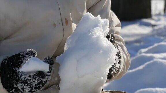 一个十几岁的男孩在冬天玩雪打雪仗把雪扔在手里明媚的冬日