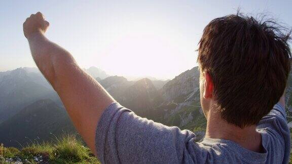 慢镜头近景男性徒步者从山顶举起双臂欣赏风景