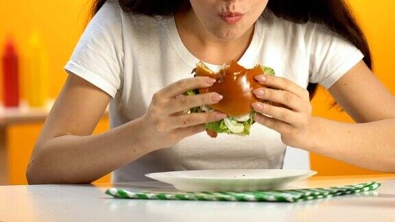 女性吃高脂肪汉堡与大胃口在快餐店节食肥胖
