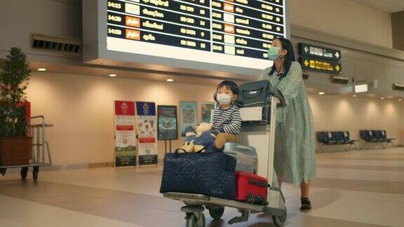 一个女人和儿子推着行李车来到机场的登机门