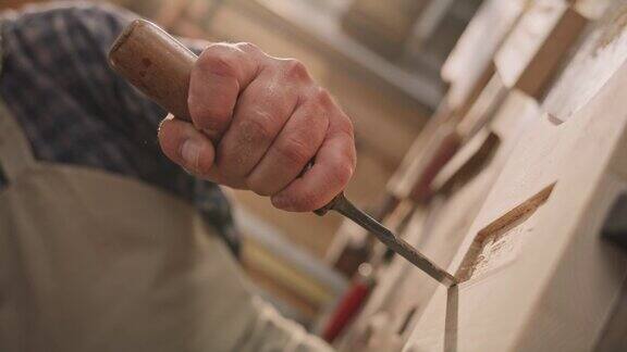 木匠用锤子敲打木凿做一个榫眼